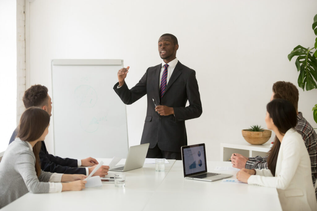 Homem negro africano apresentando uma reunião sobre eficácia de treinamento para 4 mulheres